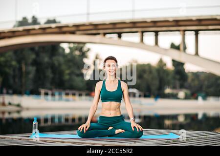 Sportlerin macht Yoga auf hölzerner Plattform Stockfoto