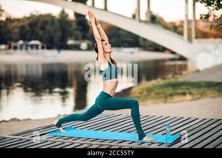 Sportlerin macht Yoga auf hölzerner Plattform Stockfoto