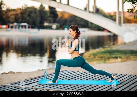 Sportlerin macht Yoga auf hölzerner Plattform Stockfoto