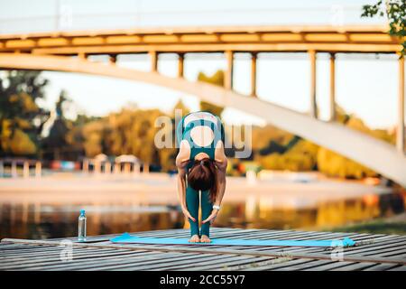Sportlerin macht Yoga auf hölzerner Plattform Stockfoto