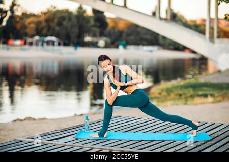 Sportlerin macht Yoga auf hölzerner Plattform Stockfoto