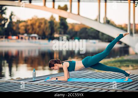 Sportlerin macht Yoga auf hölzerner Plattform Stockfoto