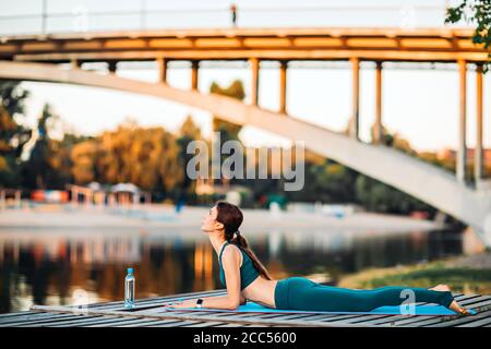 Sportlerin macht Yoga auf hölzerner Plattform Stockfoto