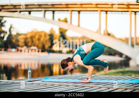 Sportlerin macht Yoga auf hölzerner Plattform Stockfoto