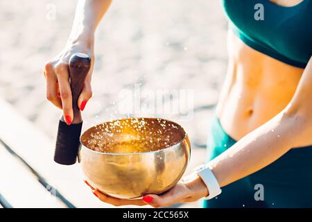 Sportlerin meditiert mit tibetischer Glocke Stockfoto