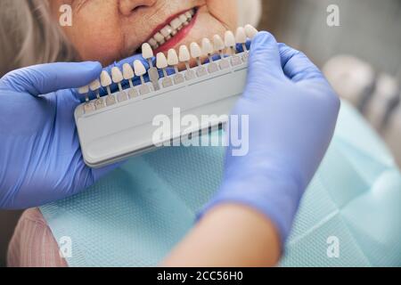 Arzt prüft und wählt die Farbe der Zähne in Der Zahnarztstuhl Stockfoto