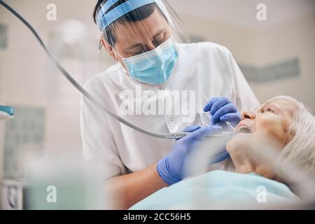 Reifer männlicher Zahnarzt, der mit seinem älteren Patienten arbeitet Stockfoto