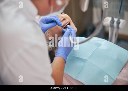 Männlicher Zahnarzt arbeitet mit Zahnarzt bohren auf Patienten Stockfoto