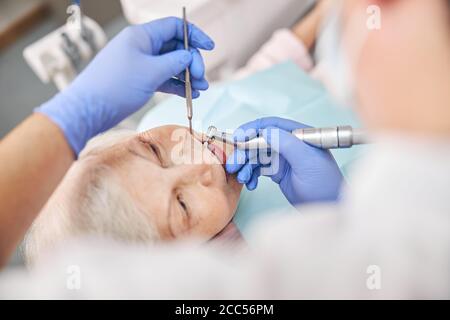 Professioneller Zahnarzt, der mit dem Patienten in der Klinik arbeitet Stockfoto