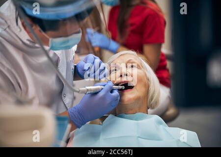 Erwachsene männliche Zahnarzt tun zahnärztliche Verfahren des Patienten an der Zahnarztpraxis Stockfoto