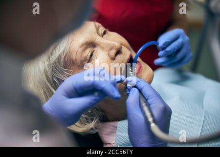 Hände des Zahnarztes in blauen Handschuhen, die ein zahnmedizinisches Werkzeug halten Stockfoto