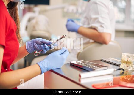 Zahnarzt Hände in Gummi-Schutzhandschuhe halten Ausrüstung für die Arbeit Stockfoto