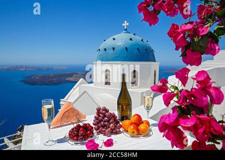 Wein und Obst für zwei auf dem Hintergrund des Meeres und der Insel Santorini. Stockfoto