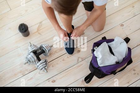 Kurzhanteln im Wohnzimmer Innenraum auf Holzboden mit Protein Shake Cup und Gym Bag Stockfoto