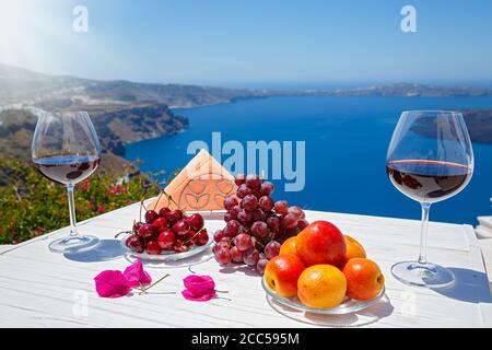 Obst und zwei Gläser Rotwein auf dem Hintergrund Vom Meer von Santorini Stockfoto