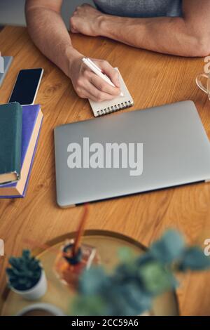 Mann, der in einem kleinen Notizbuch mit Stift schreibt Stockfoto