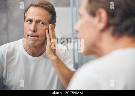 Mann untersucht die Haut auf seinem Gesicht Stockfoto