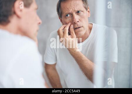 Ernster Mann, der aufmerksam auf seine Reflexion schaut Stockfoto