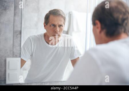 Traurige Person, die sich im Spiegel untersucht Stockfoto