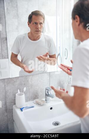 Angespannter Mann, der Tabletten in seiner Handfläche hält Stockfoto