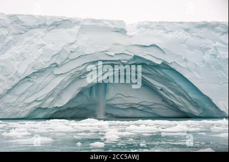 Ein Abschnitt der glazialen Meereswand ist weggebrochen und zeigt einen Wasserfall.die zerbrochenen Eisfragmente können im Vordergrund driften gesehen werden.Klimakrise. Stockfoto