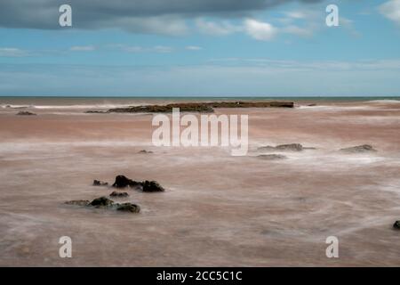 Lange Exposition der Gezeiten über Felsen auf Budeigh Salterton in Devon Stockfoto