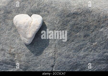 Weißer Herzstein auf grauem Felsen Stockfoto