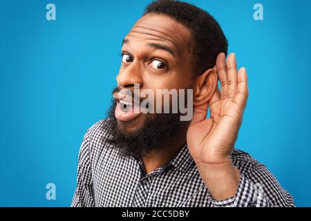 Neugierig stattlichen Afro Kerl hält Hand in der Nähe seines Ohrs Stockfoto