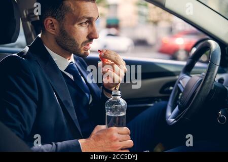 Stolzer junger Mann sitzt in seinem Auto Stockfoto