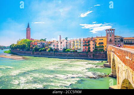 Verona Stadtbild mit Gebäuden am Etsch Flussufer, Glockenturm Campanile di Santa Anastasia katholische Kirche, Ponte Pietra Steinbrücke im historischen Stadtzentrum, blauer Himmel, Region Venetien, Italien Stockfoto