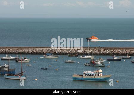 Offshore RNLI Torbay Rettungsboot nach der Rettung, außerhalb Wellenbrecher mit festmachen Yachten und Boote innerhalb Wellenbrecher; Brixham, Devon, Großbritannien Stockfoto