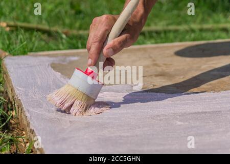 Arbeiter Hand hält eine Bürste und legt Grundierung auf Betonboden. Garten Reparaturen und Bau. Stockfoto