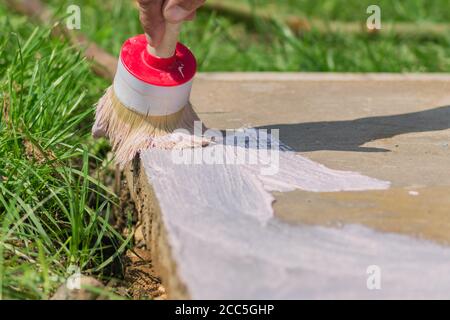 Arbeiter Hand hält eine Bürste und legt Grundierung auf Betonboden. Garten Reparaturen und Bau. Stockfoto