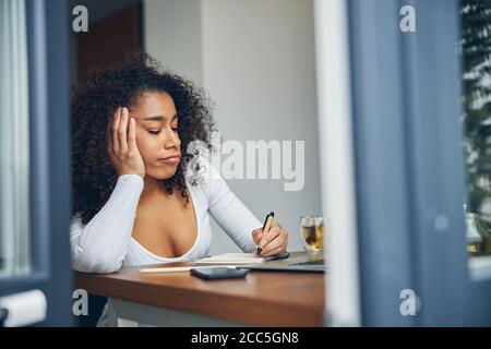 Schöne afroamerikanische Frau sitzen und schreiben Stockfoto