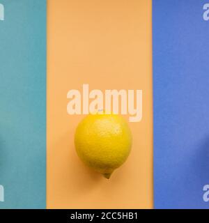 Zitrone auf farbenprächtigem orange, blauem und grünem Hintergrund, Draufsicht, minimales flaches Lay. Stockfoto
