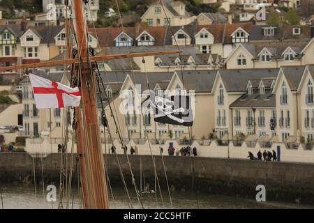 Flagge von St. George und Jolly Roger, die von Holzkreuzbalken des Holzbootes fliegen, Brixham, Devon, UK Stockfoto