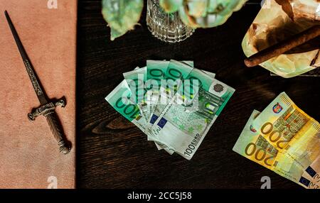 Hundert Euro Scheine auf einem Plüschtisch mit Zigarre gelegt Und Dolch Stockfoto