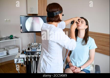 Weibliche Otolaryngologin und Patientin im Büro, Exa Stockfoto
