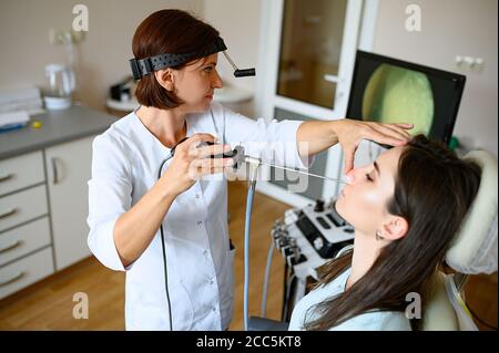 Weibliche Otolaryngologin und Patientin im Büro, Exa Stockfoto