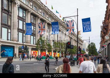 Leute draußen in der Oxford Street, in der Nähe des Kaufhauses Selfridges. „Danke“-Banner hängen über der Straße, um wichtige Mitarbeiter während der Pandemie von Covid-19 zu ehren. Stockfoto