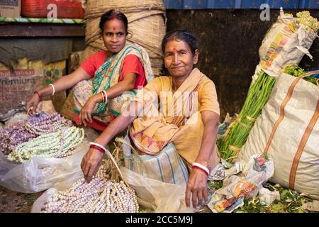 Verkäufer kaufen und verkaufen wunderschöne Girlanden aus Ringelblumen und Lotusblumen auf dem Mullick Ghat Blumenmarkt in Kalkutta, Indien, Südostasien. Stockfoto