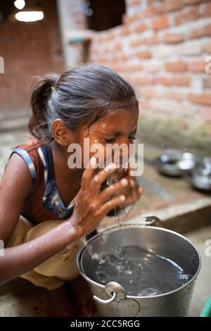 Anu Kumari (10) wäscht ihr Gesicht mit Wasser aus dem neuen Wasserhahn, den ihre Mutter vor kurzem im Haus der Familie in Bihar, Indien, installiert hatte. Die meisten Menschen im ländlichen Indien können kein Wasser in ihrem eigenen Haus laufen lassen, aber die Beteiligung der Familie Anand an Partnership Bihar hat ihren Lebensstandard erheblich erhöht. Partnership Bihar ist eine lutherische Weltenhilfe-Initiative, die bessere Anbaumethoden, hochwertiges Saatgut, verbesserte Ernährung für Familien und Selbsthilfegruppen für Mikrofinanzierungen in Gemeinden in einem der ärmsten indischen Staaten bringt. Pradan (Professionelle Hilfe für Entwicklung Stockfoto