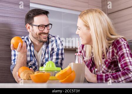 Glückliches Paar, das natürlichen Orangensaft in der Küche und macht Genießen Sie ihre Zeit Stockfoto