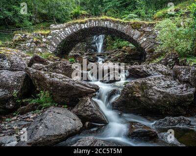 Eine Papppferdbrücke über einen Nebenfluss unter einem Wasserfall am Südufer des Flusses Lyon. Dies ist lokal bekannt als die römische Brücke, obwohl actua Stockfoto