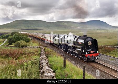 Ribblehead, Yorkshire, Großbritannien. August 2020. Mitten in den Sommerferien, eines von drei Dampfzug-Specials diese Woche auf der berühmten Settle-Carlisle-Bahnlinie. Vintage Dampflokomotive 'Britannia' ist hier zu sehen schleppen 'der Fellsman' Sonderzug nördlich von Settle in Richtung Carlisle, auf einer Reise, die in Crewe begann. Es ist hier abgebildet, nachdem es gerade das Ribblehead Viadukt im Yorkshire Dales National Park überquert hat. Inglleborough Peak ist im Hintergrund rechts zu sehen. Quelle: John Bentley/Alamy Live News Stockfoto