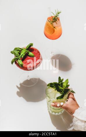 Beliebte Bar Sommer Eis alkoholische Cocktails. Gin-Tonic, Aperol Spritz und Erdbeerbasil Margarita in Gläsern und Womans Hand hält Glas über Plai Stockfoto