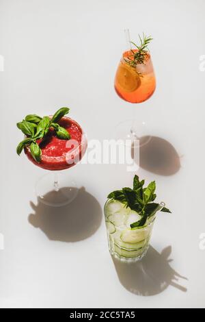 Beliebte Bar Sommer Eis alkoholische Cocktails. Gin-Tonic, Aperol Spritz und Erdbeerbasil Margarita in Gläsern auf schlichtem weißen Hintergrund mit Schatten Stockfoto