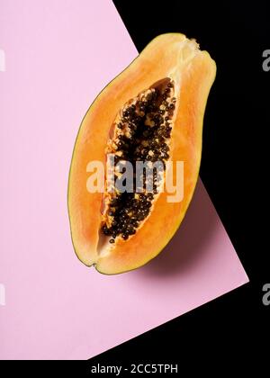 Stillleben Komposition mit Papaya auf rosa und schwarzem Hintergrund. Stockfoto