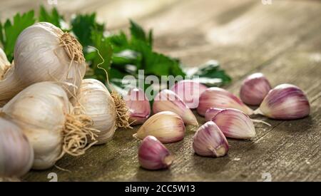 Frische reife Knoblauchzehen und Zwiebeln und Sellerie Blätter in Schüssel und vintage alten Holztisch. Gesunde Bio-Lebensmittel, Vitamine, Bio-Viands, natürliche Backgro Stockfoto