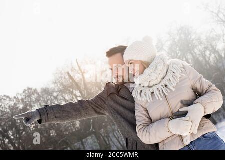 Glückliches Paar, das den Winterschnee im Park auf genießt Ein schöner Wintertag Stockfoto